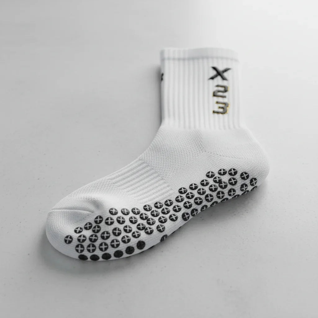 Single white X23 grip sock with black anti-slip dots on sole, displayed on plain light gray surface