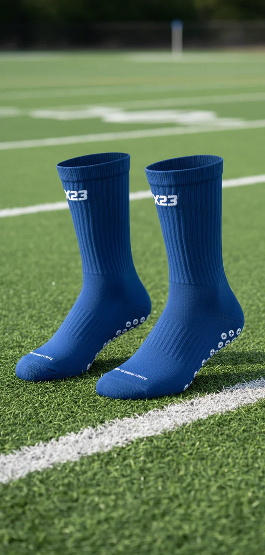 Pair of blue X23 grip socks with high-density traction on green sports field turf